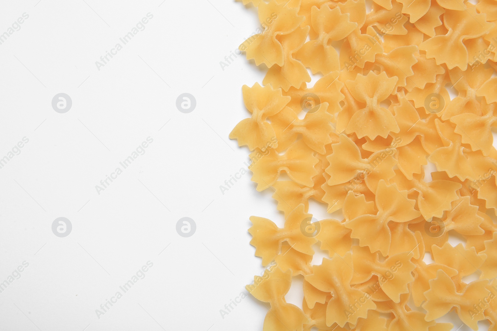 Photo of Raw farfalle pasta on white background, top view. Space for text
