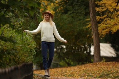 Photo of Happy woman walking in autumn park. Space for text
