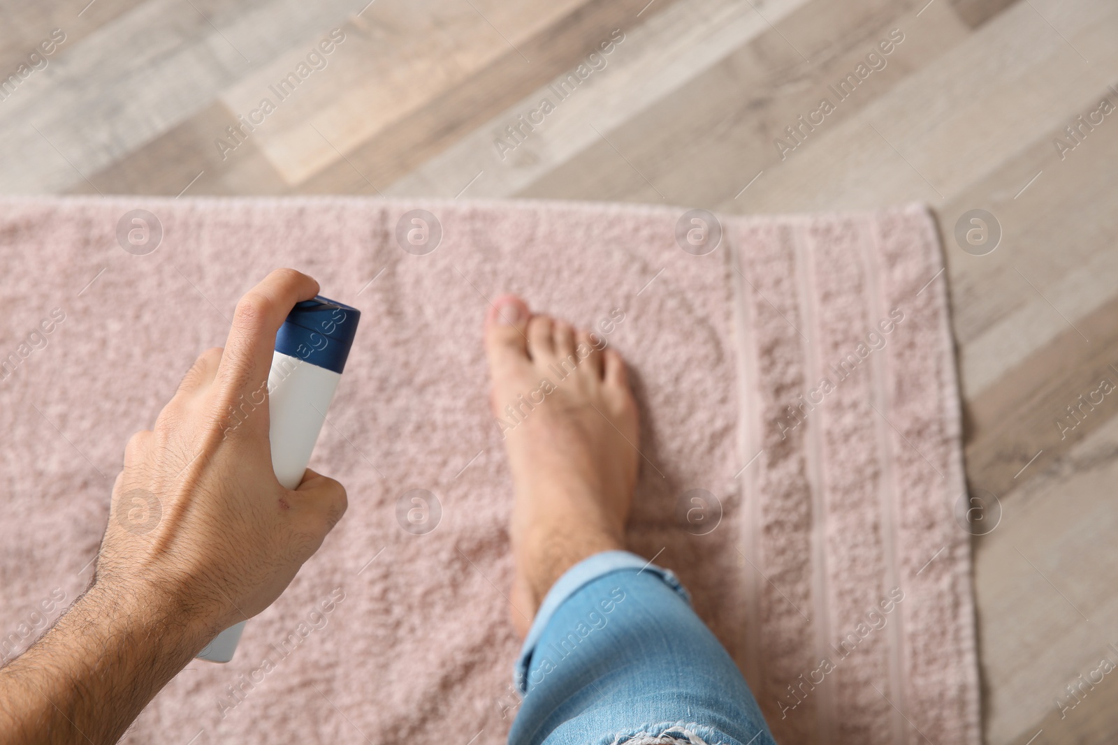 Photo of Young man using deodorant for feet at home, closeup