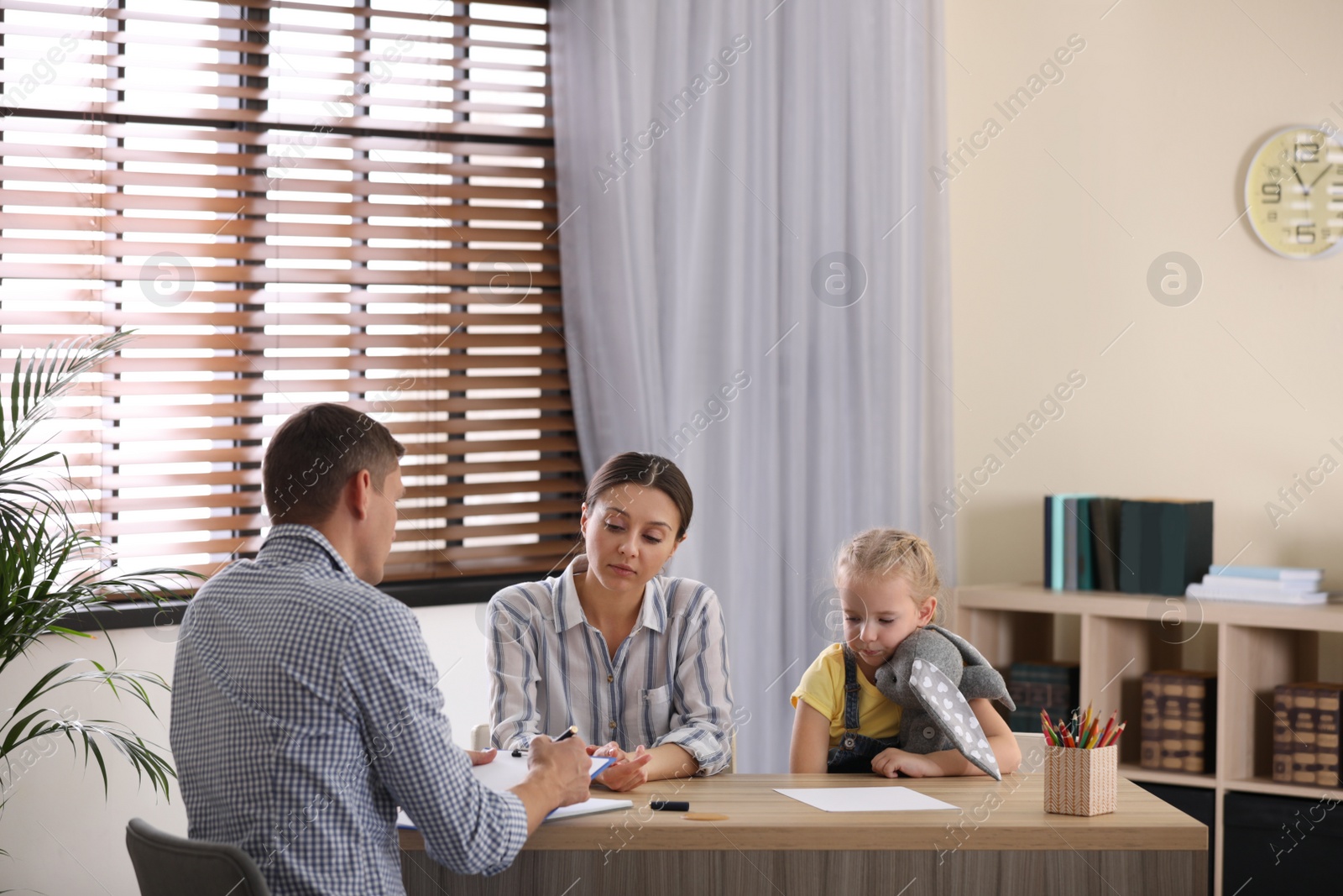 Photo of Child psychotherapist working with little girl and her mother in office