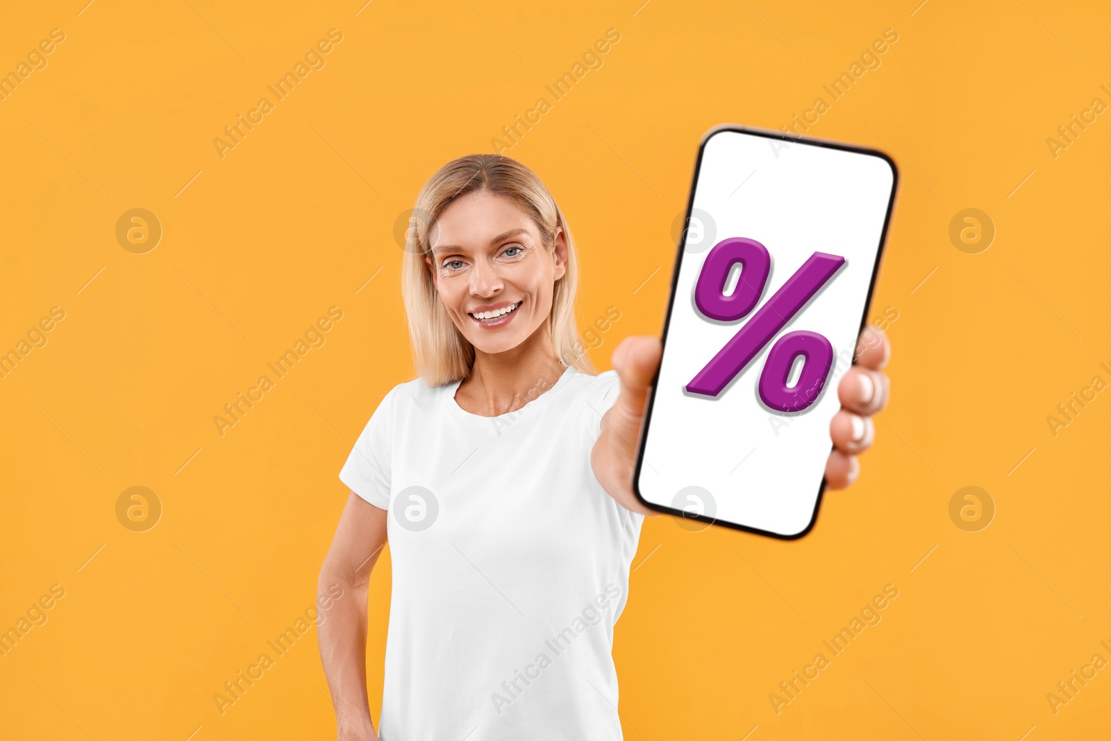 Image of Discount, offer, sale. Woman showing mobile phone with percent sign on screen, orange background