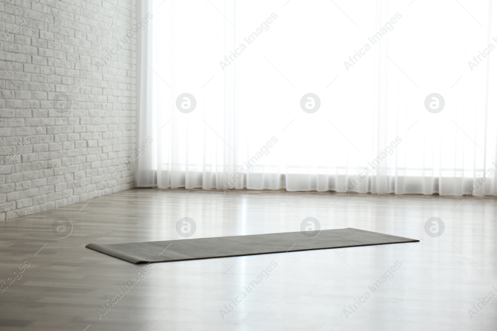 Photo of Unrolled grey yoga mat on floor in room