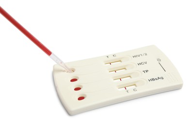 Photo of Dropping blood sample onto disposable express hepatitis test cassette with pipette on white background