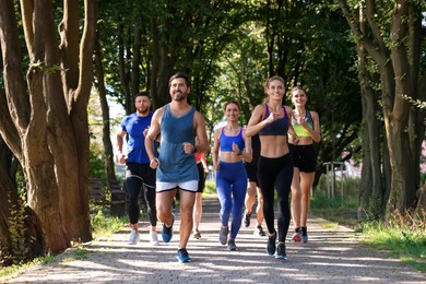 Group of people running in park on sunny day