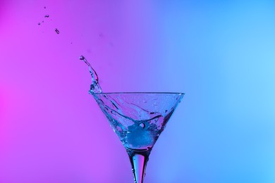 Glass of martini with ice and splashes in neon lights