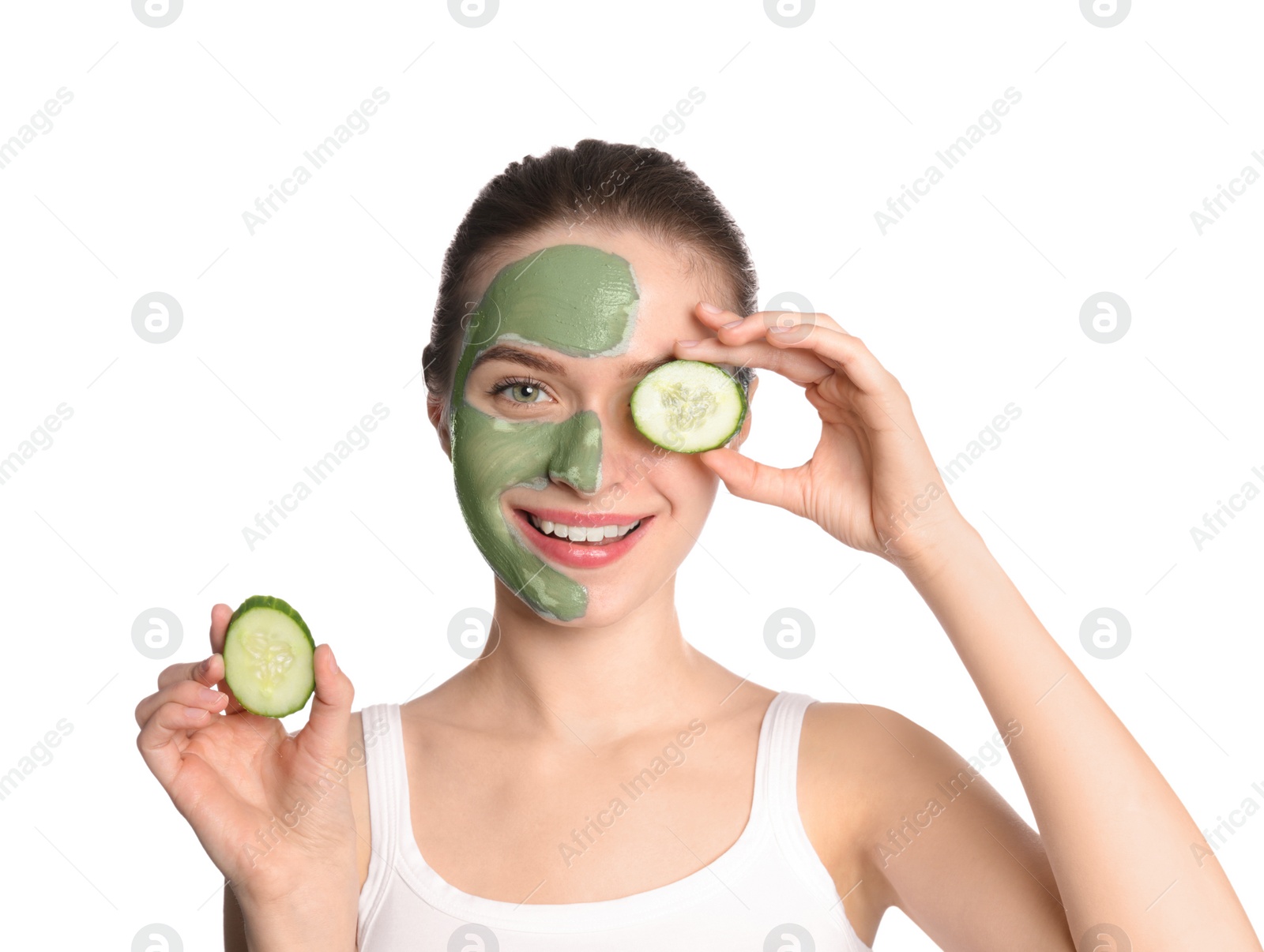 Photo of Young woman with clay mask on her face holding cucumber slices against white background. Skin care