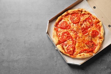 Photo of Cheese pizza in carton box on grey background, top view with space for text. Food delivery service