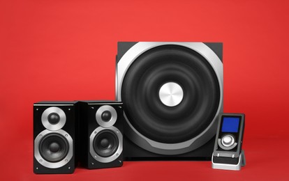 Photo of Modern powerful audio speaker system with remote on red background