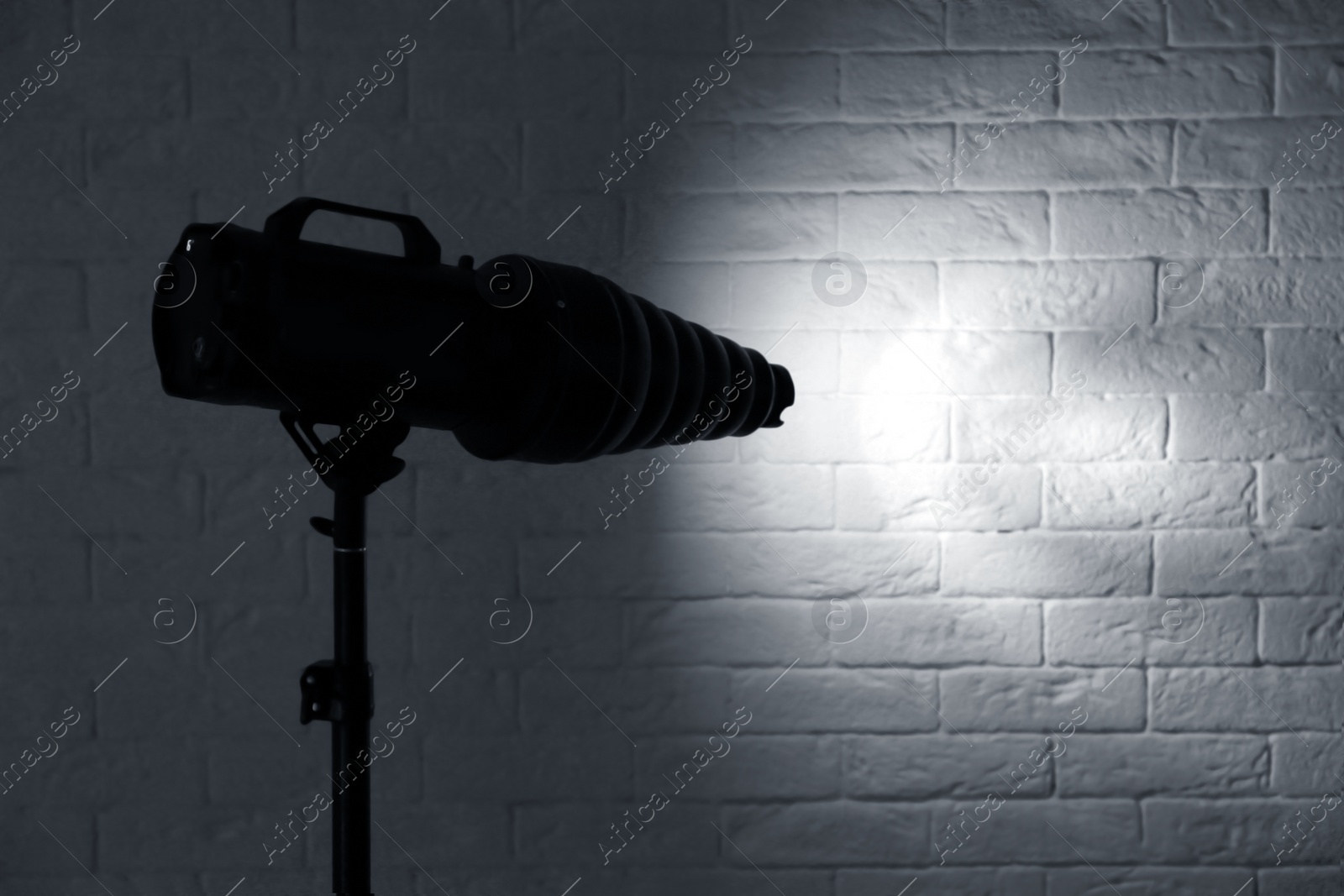 Photo of Professional photo studio lighting equipment near brick wall. Space for text