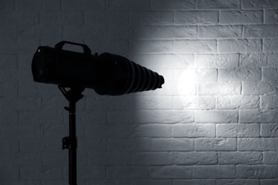 Photo of Professional photo studio lighting equipment near brick wall. Space for text