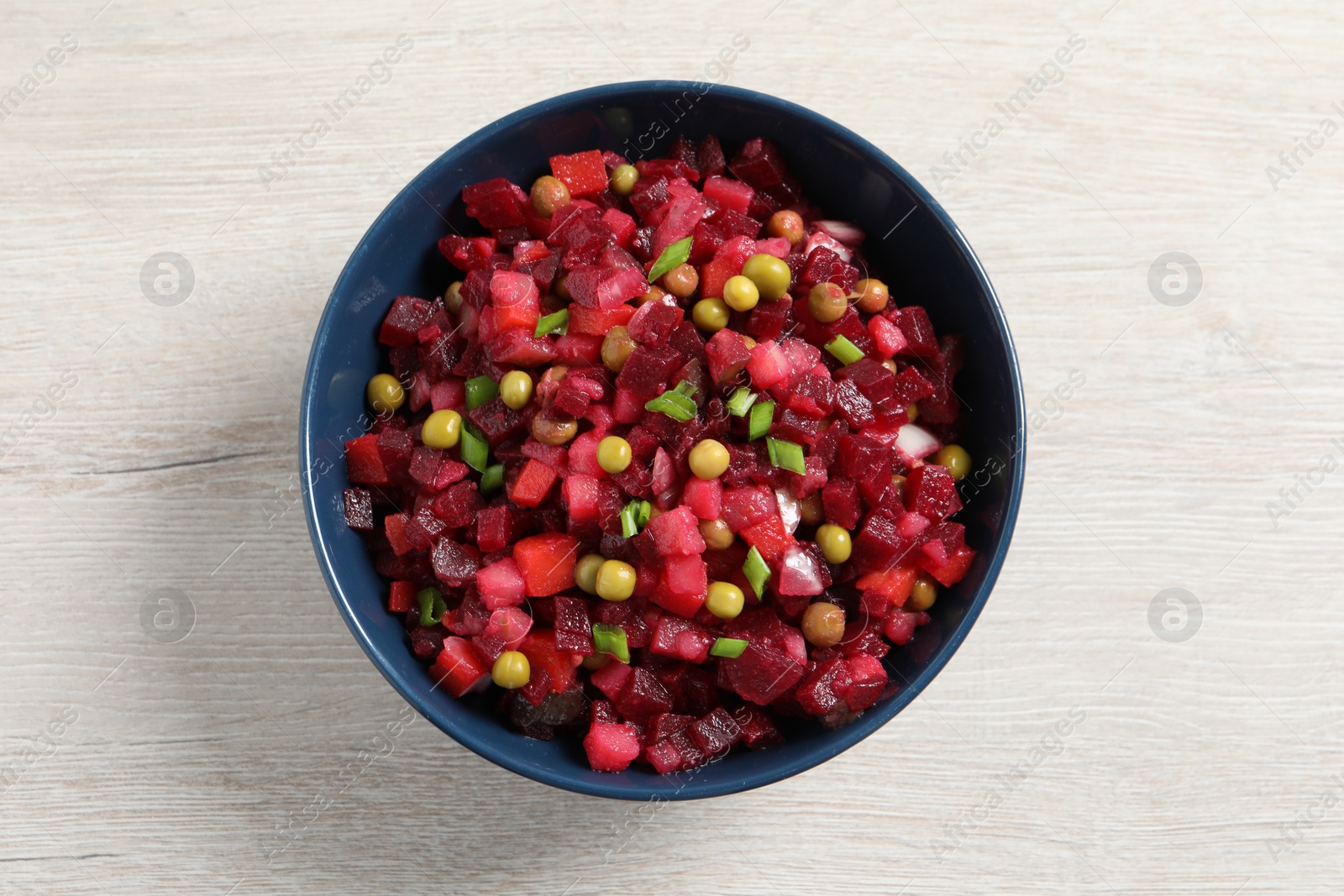 Photo of Bowl of delicious fresh vinaigrette salad on white wooden table, top view