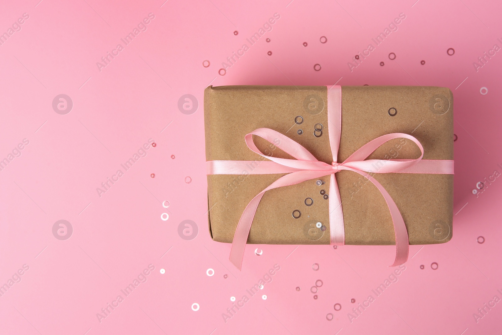 Photo of Beautiful gift box with bow and confetti on pink background, top view. Space for text