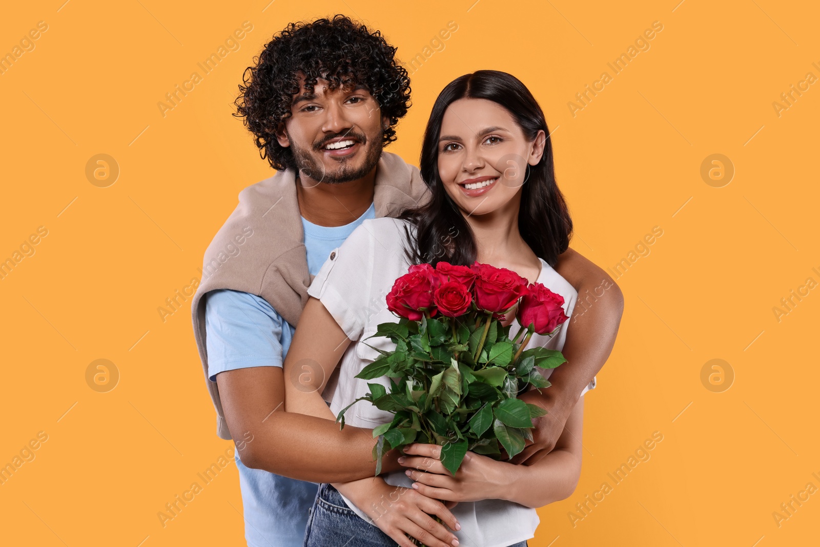 Photo of International dating. Happy couple with bouquet of roses on yellow background