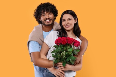 Photo of International dating. Happy couple with bouquet of roses on yellow background