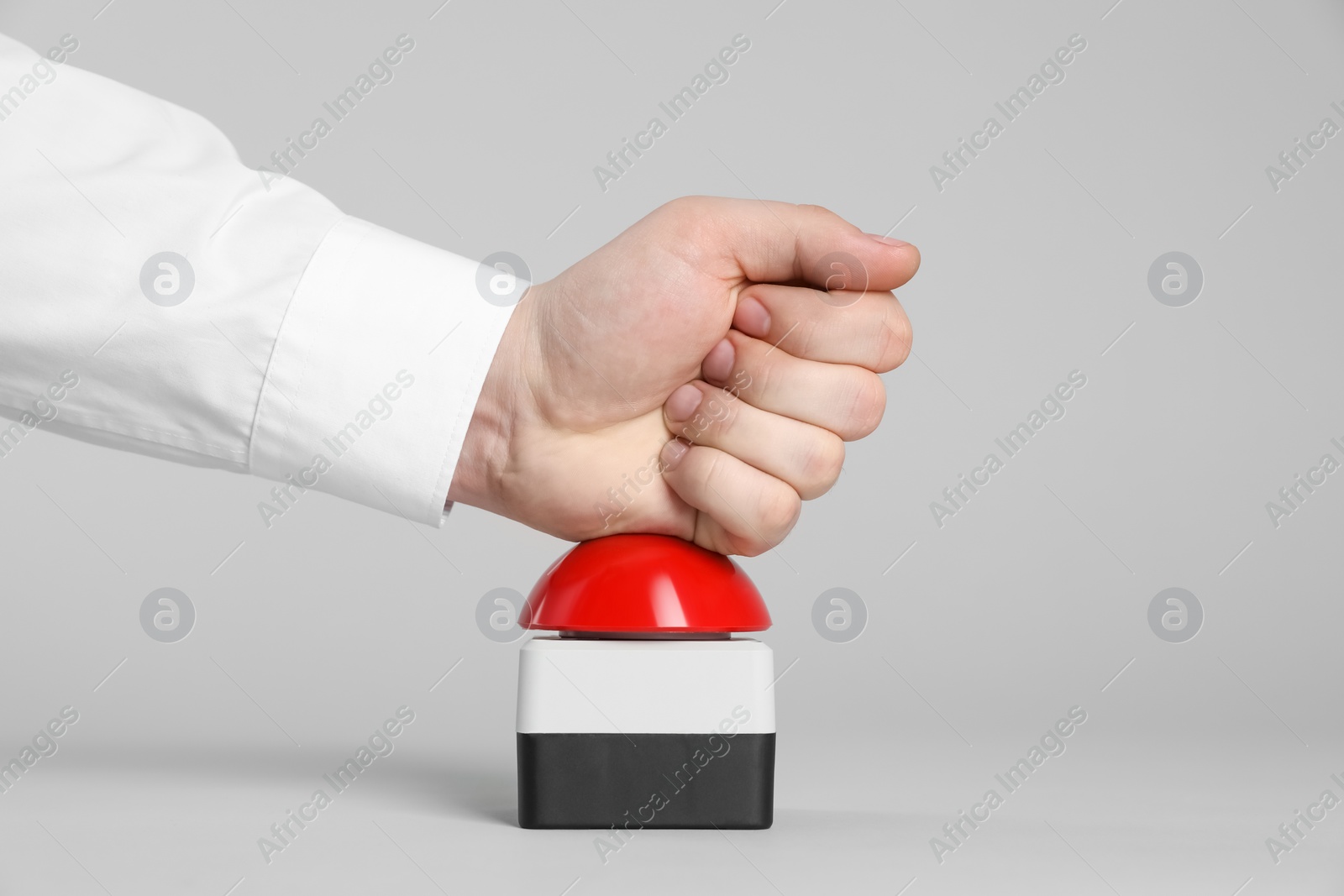 Photo of Man pressing red button of nuclear weapon on light gray background, closeup. War concept