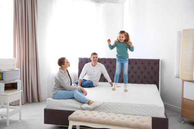 Photo of Happy family choosing mattress in furniture store