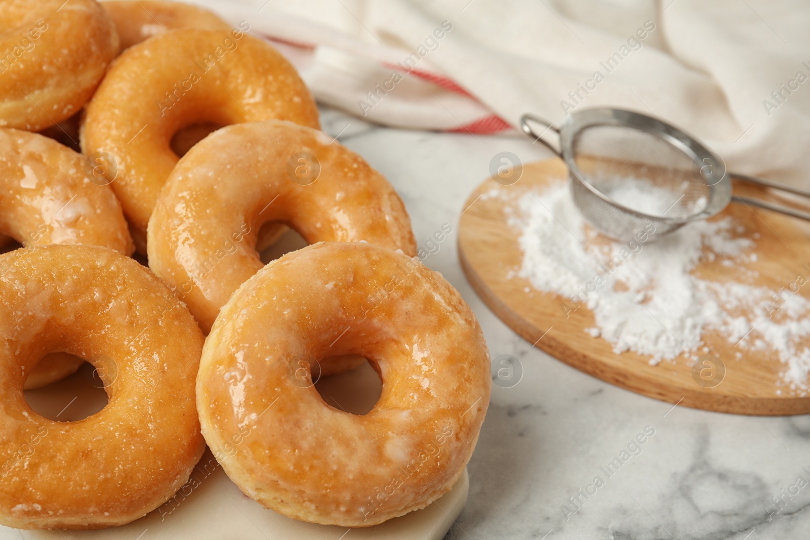 Photo of Delicious glazed donuts on marble table, closeup