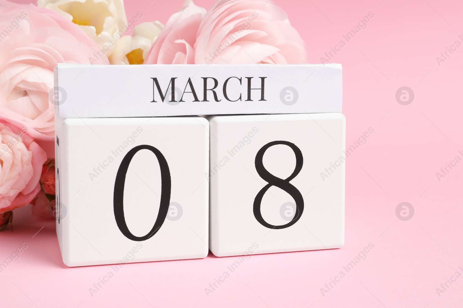 Photo of International Women's day - 8th of March. Wooden block calendar and beautiful flowers on pink background