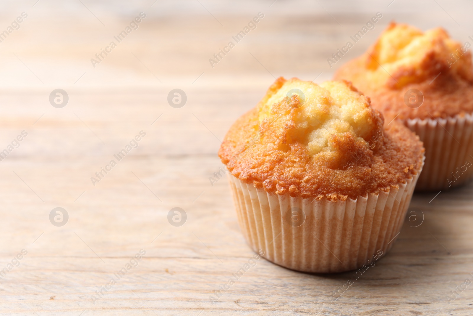 Photo of Delicious sweet muffins on wooden table, closeup. Space for text