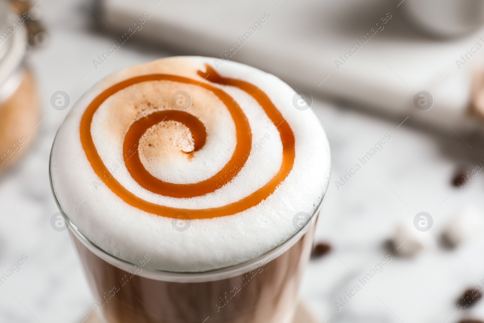 Photo of Glass with delicious caramel latte on table, closeup