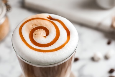 Photo of Glass with delicious caramel latte on table, closeup