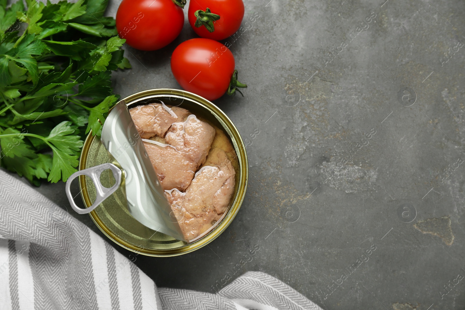 Photo of Flat lay composition with tin can of tasty cod liver and different products on grey table. Space for text