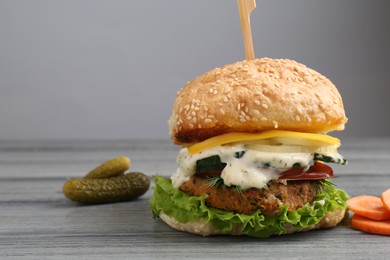 Photo of Delicious vegetarian burger and ingredients on grey wooden table