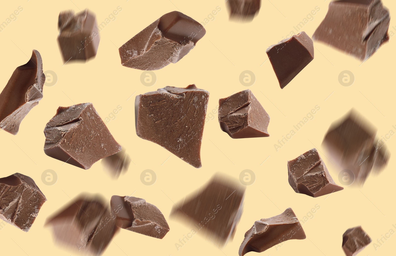 Image of Delicious chocolate pieces falling on yellow background