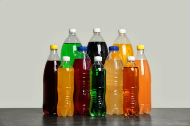 Photo of Bottles of soft drinks on table against grey background