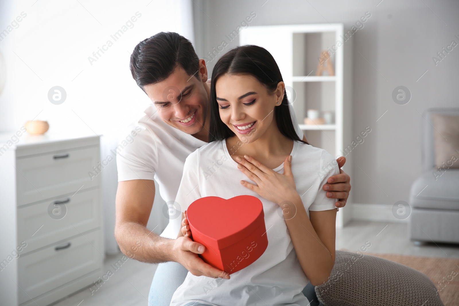 Photo of Man presenting gift to his beloved woman at home. Valentine's day celebration