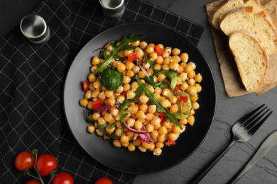 Photo of Delicious fresh chickpea salad served on black table, flat lay