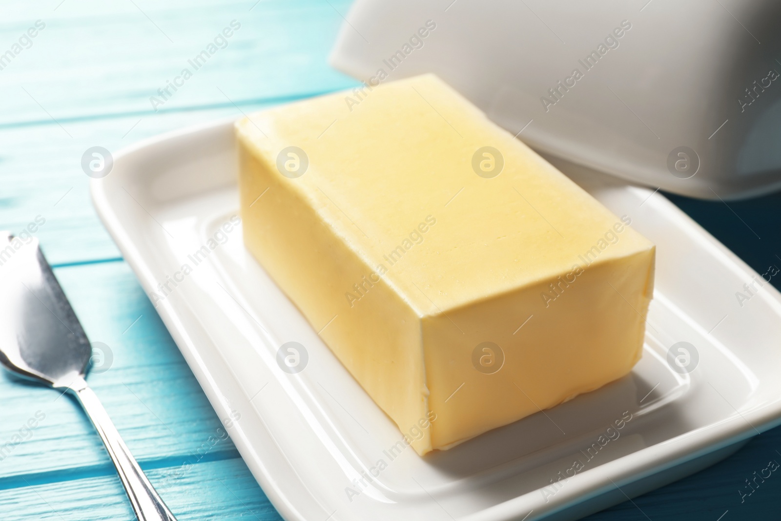 Photo of Dish with fresh butter and knife on wooden background, closeup