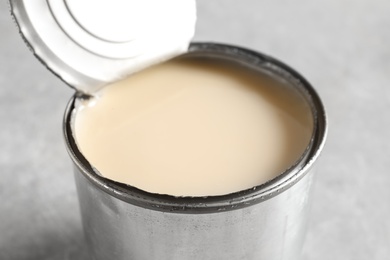 Photo of Tin can with condensed milk on grey background, closeup. Dairy product