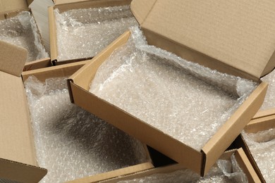 Photo of Many open cardboard boxes with bubble wrap on floor, closeup. Packaging goods