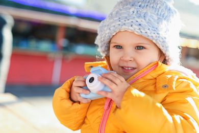 Photo of Cute little photographer with toy camera outdoors