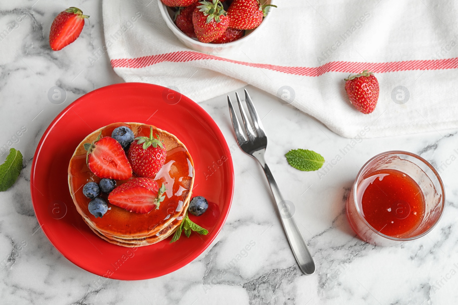 Photo of Delicious pancakes with fresh berries and syrup served on white marble table, flat lay