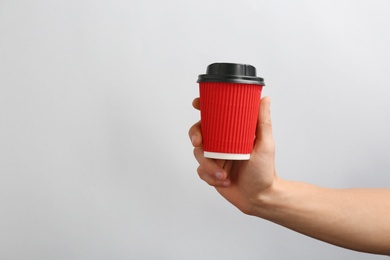 Photo of Man holding takeaway paper coffee cup on light background. Space for design