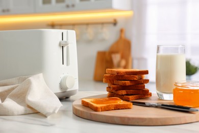 Photo of Breakfast served in kitchen. Toaster, crunchy bread, honey and milk on white table