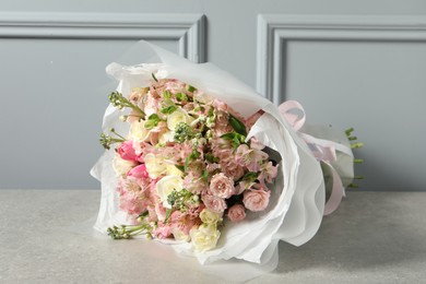 Photo of Beautiful bouquet of fresh flowers on table near grey wall