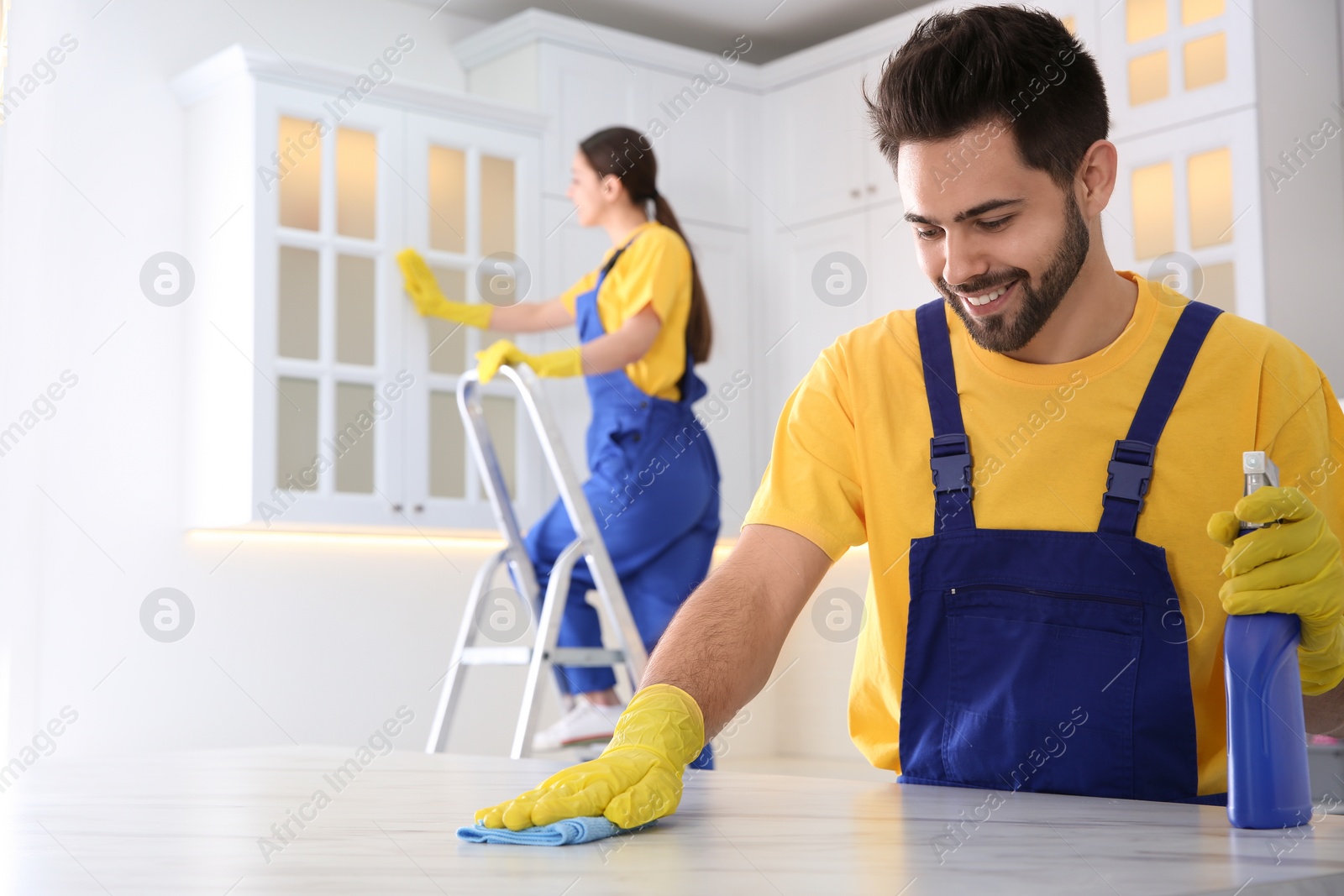 Photo of Professional young janitor cleaning table in kitchen