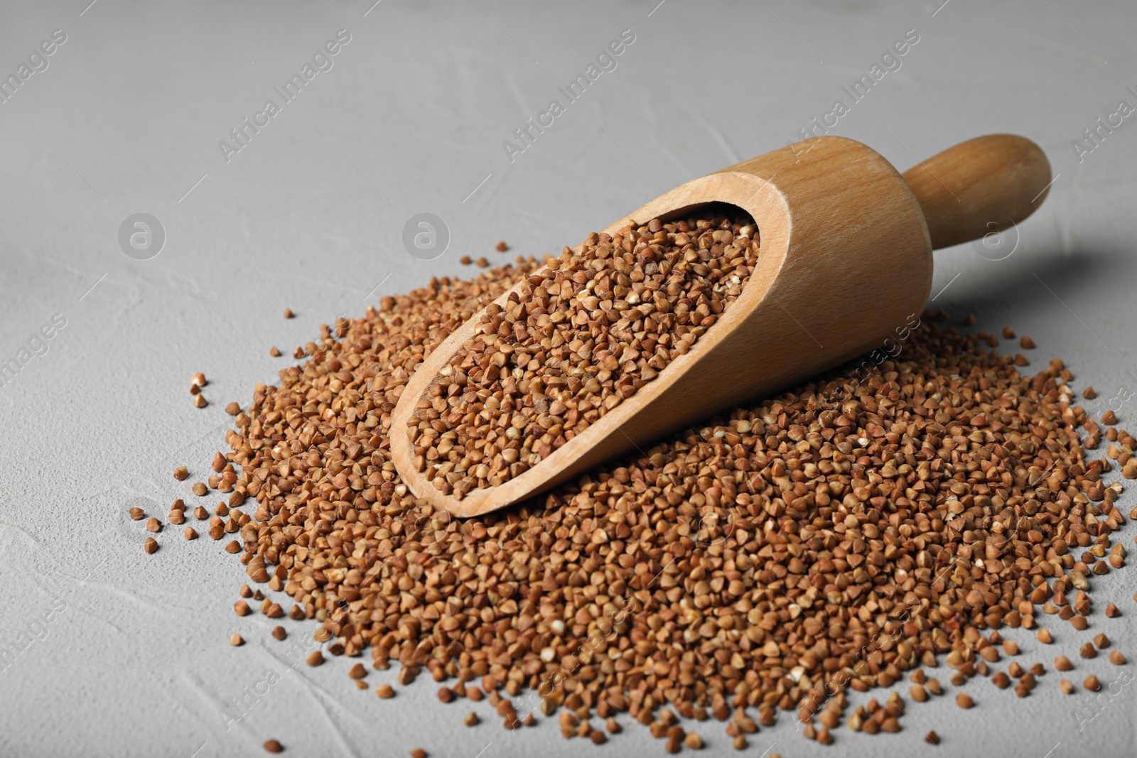 Photo of Wooden scoop with uncooked buckwheat on table