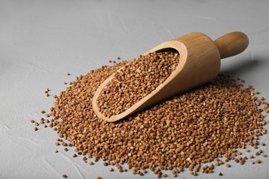 Photo of Wooden scoop with uncooked buckwheat on table