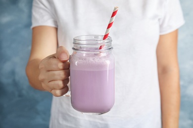 Photo of Woman with mason jar of delicious milk shake on color background, closeup