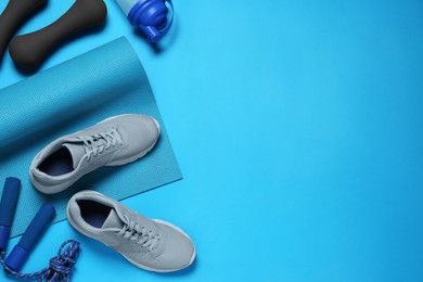 Photo of Exercise mat, shoes, dumbbells, shaker and skipping rope on turquoise background, flat lay. Space for text