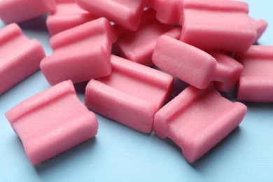 Photo of Tasty pink chewing gums on light blue background, closeup