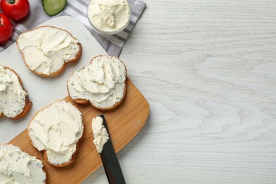 Toasted bread with cream cheese on white wooden table, flat lay. Space for text