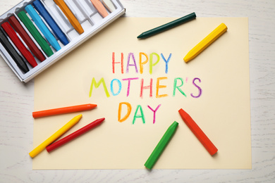 Photo of Greeting card for Mother's day and crayons on white wooden background, flat lay