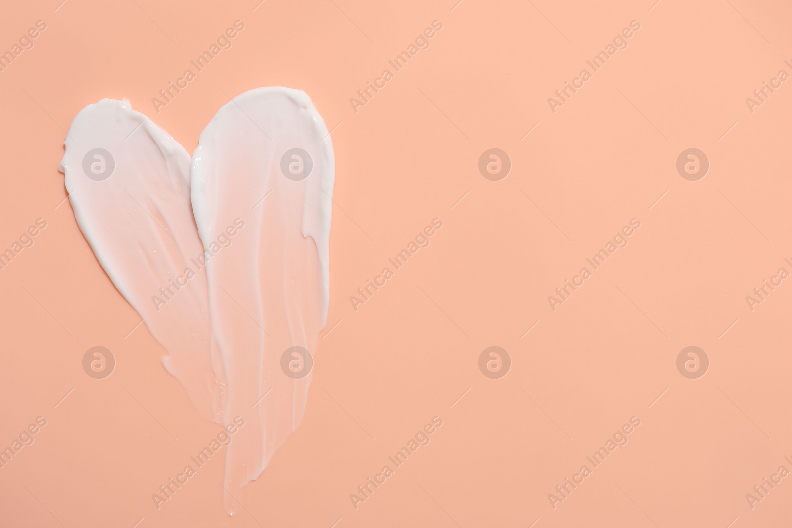 Photo of Samples of face cream on coral background, top view. Space for text