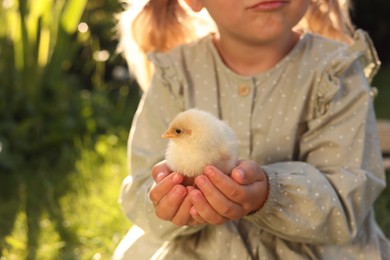 Photo of Little girl with cute chick outdoors, closeup. Baby animal