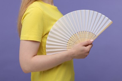 Photo of Woman with hand fan on violet background, closeup